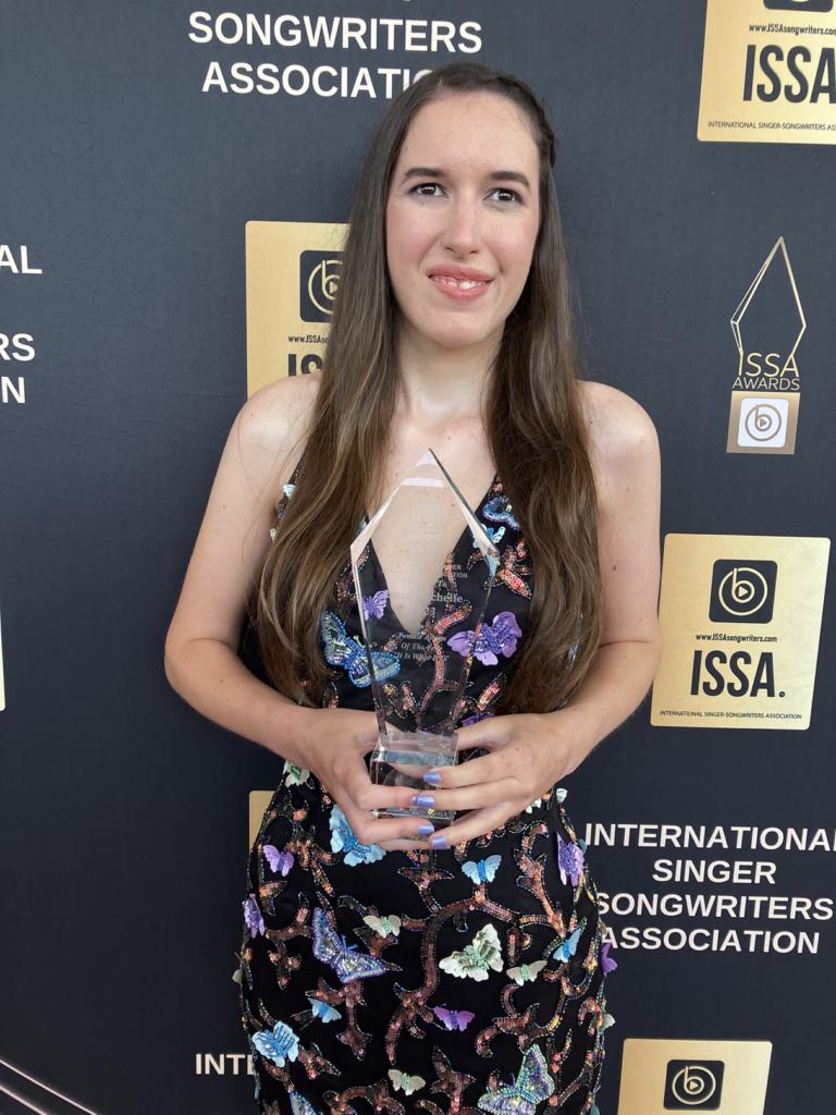 Demi Michelle standing with her ISSA Awards crystal on the red carpet