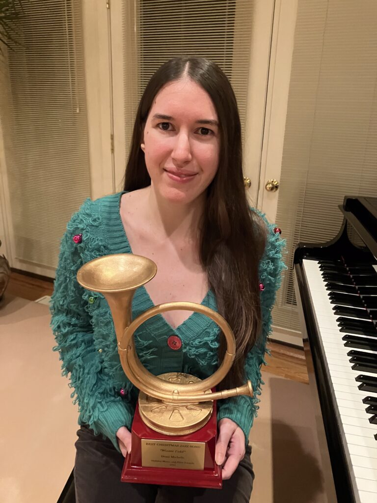 Demi Michelle smiling with her award by her piano