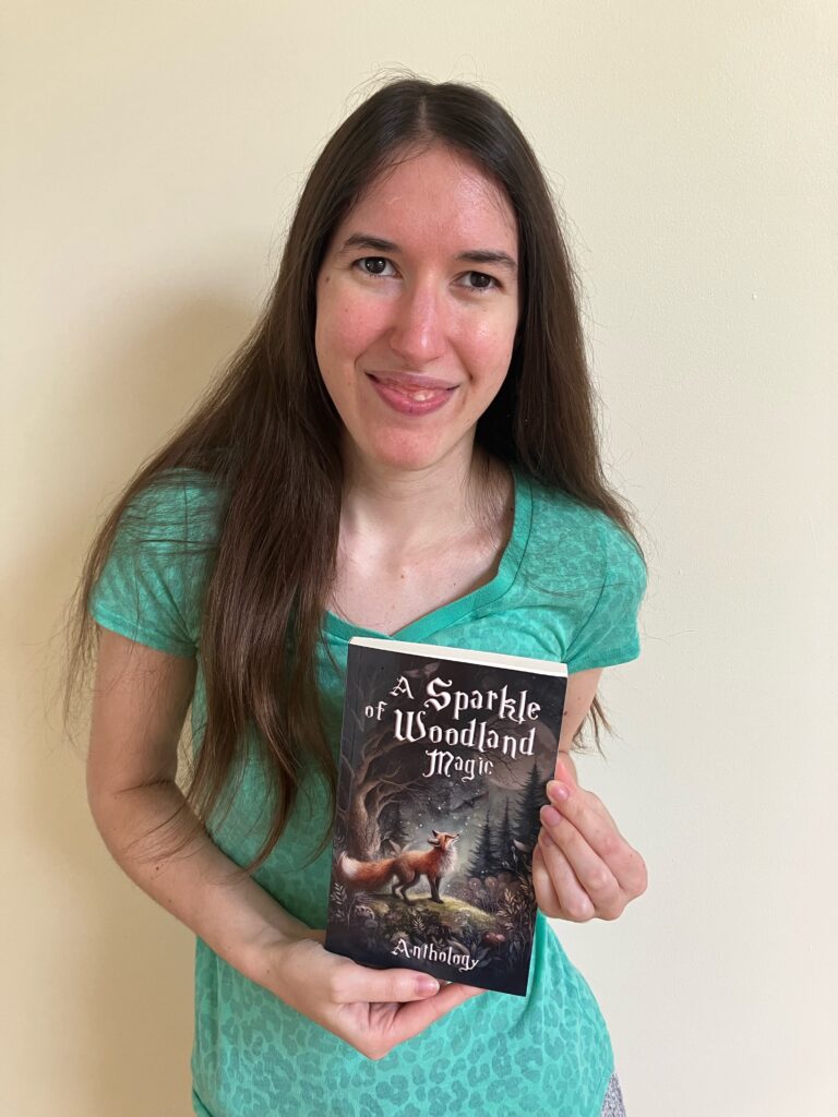 Demi smiling with her copy of A Sparkle of Woodland Magic
