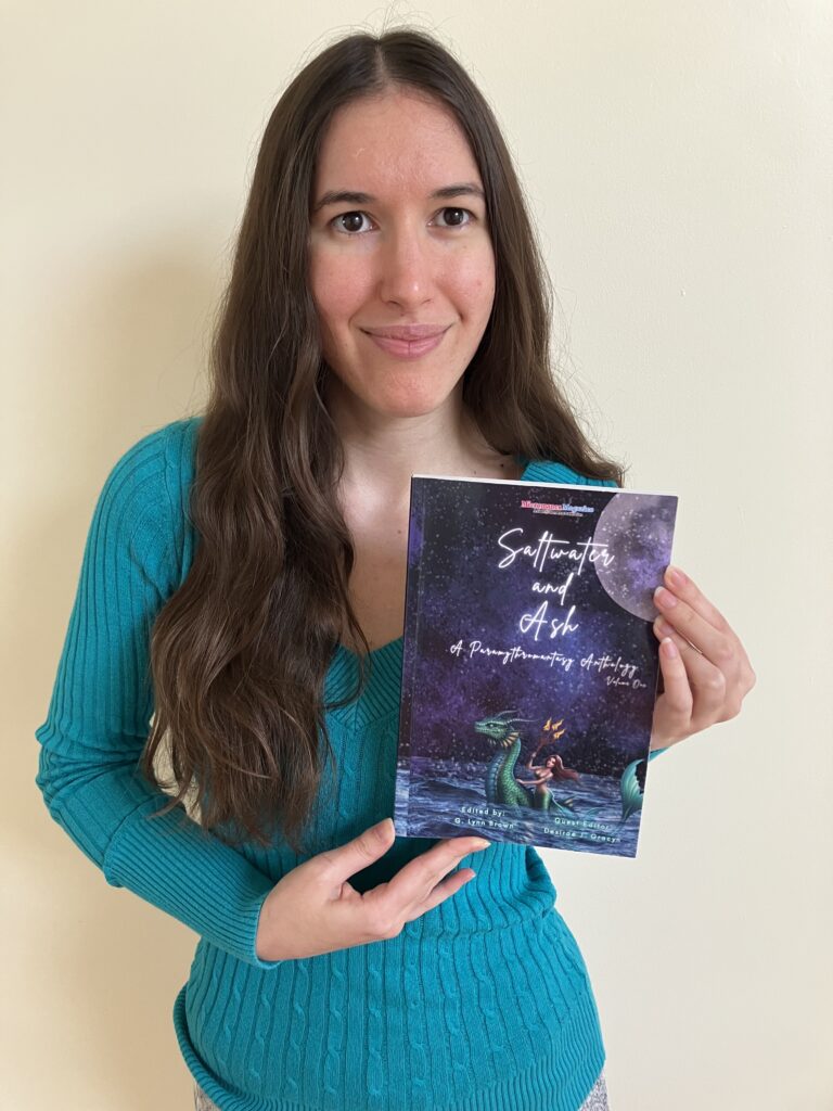 Demi smiling with her copy of Saltwater and Ash